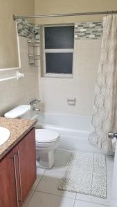 La salle de bains est pourvue de toilettes, d'une baignoire et d'un lavabo. dans l'établissement Glam 2 Bedroom Apartment Close to NSU in Cooper City, à Cooper City