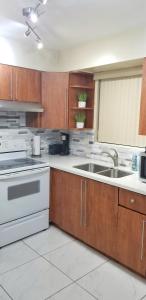 a kitchen with wooden cabinets and a sink at Glam 2 Bedroom Apartment Close to NSU in Cooper City in Cooper City