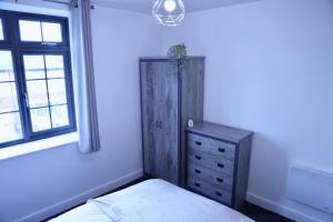 ein Schlafzimmer mit einem Bett, einer Kommode und einem Fenster in der Unterkunft Nottingham Brand New 1BR Apt w/ Full Kitchen City in Nottingham