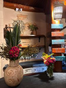 zwei Vasen mit Blumen auf einem Tisch mit Büchern in der Unterkunft Na Casa 11 - Pousada e Hostel in Arraial d'Ajuda