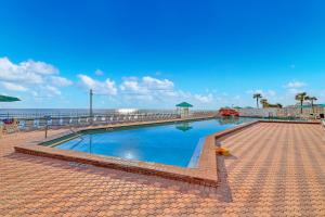 a swimming pool next to a beach with the ocean at Harbour Beach Resort 611 in Daytona Beach