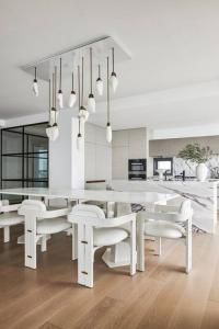 uma cozinha branca com mesas brancas e cadeiras brancas em The Jewel, A designer Condo in the Sky em Gold Coast