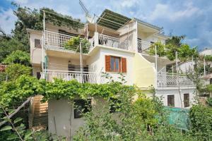 a white house with white balconies and trees at Apartments by the sea Stanici, Omis - 1028 in Tice