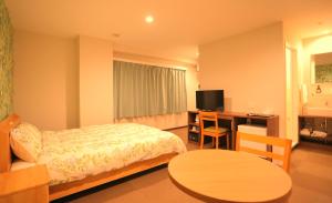 a bedroom with a bed and a desk with a television at Yuyukan in Chitose