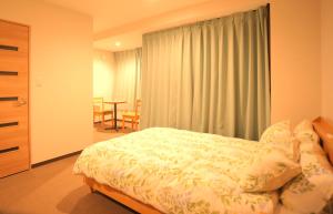 a bedroom with a bed and a window with a table at Yuyukan in Chitose