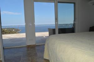 um quarto com uma cama e uma varanda com portas de vidro deslizantes em Petit coin de Paradis a cote de Monaco em Roquebrune-Cap-Martin
