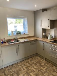 a kitchen with white cabinets and a sink and a window at Cozy & Spacious home In the heart of Snowdonia in Llanddeiniolen