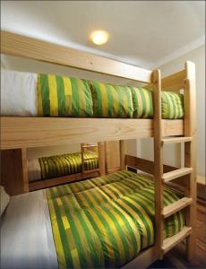 2 Etagenbetten mit grüner und gelber gestreifter Bettwäsche in der Unterkunft Bear Packer Hostel in Cusco