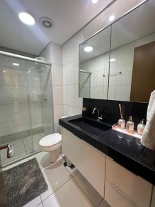 a bathroom with a sink and a toilet and a mirror at Apartamento Luxo St Bueno in Goiânia