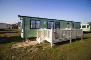 uma casa verde com um alpendre e uma cerca branca em 8 Berth Caravan With Wifi At Sunnydale Park In Skegness Ref 35220kc em Louth