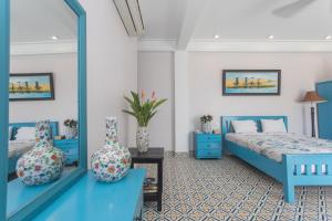 1 dormitorio con 2 camas azules y espejo en Grace Boutique Resort, en Mui Ne
