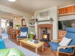 un soggiorno con camino e sedie blu di Meadow Pit Cottage a Topsham