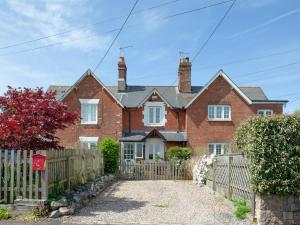 una casa de ladrillo rojo con una valla de madera en Meadow Pit Cottage en Topsham