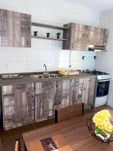 a kitchen with wooden cabinets and a sink and a table at Cheerful 2-bedroom home with patio near city center in Willemstad