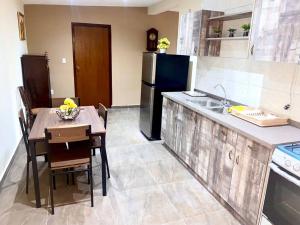 a kitchen with a table and a black refrigerator at Cheerful 2-bedroom home with patio near city center in Willemstad