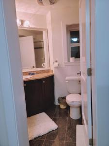 uma casa de banho com um WC, um lavatório e um espelho. em Peaceful Private Room em Surrey