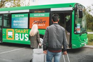 mężczyzna i kobieta idą w kierunku zielonego autobusu w obiekcie Bus Hostel Reykjavik - Reykjavik Terminal w Reykjavík