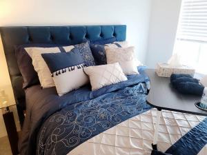 Una cama azul con muchas almohadas. en Peaceful Private Room en Surrey