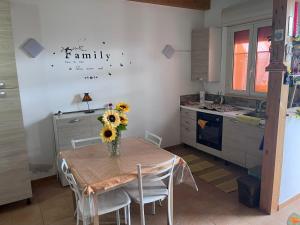 a kitchen with a table with a vase of flowers on it at Villino luca in Isola delle Femmine