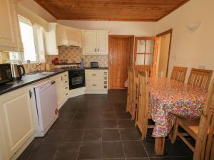 una cocina con armarios blancos y una mesa. en Creeslough View, en Creeslough