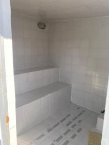 a white tiled bathroom with a shelf in it at alojamiento rural finca ayapel in Verdún