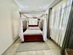 1 cama con dosel en una habitación con ventanas en The Angelique Oasis en Arusha