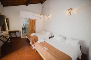 a bedroom with two beds and a table and a window at Hotel Archangelus in Mompós