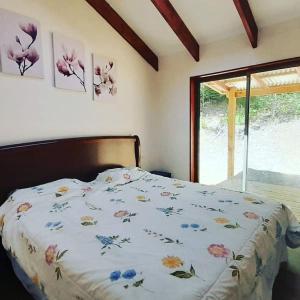 1 cama con edredón de flores en un dormitorio en Cafeteria y Cabañas Eluney - Cabaña Laurel, en Pucón