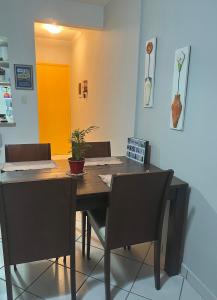 a dining room table with two chairs and a table with a plant at Nosso apê no Guarujá - Unidade Aquário in Guarujá