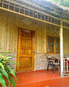 una casa con una puerta de madera y un banco en un porche en Ninh Binh Bamboo Farmstay, en Ninh Binh