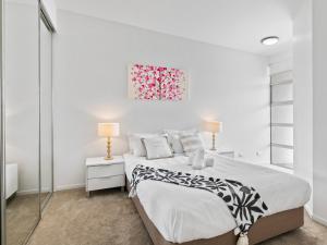 a white bedroom with a bed and a painting on the wall at Artsy Destination Compact & Cosy 2 BR Apart at Valley in Brisbane