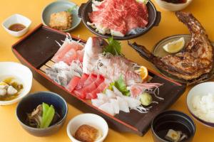 a table topped with plates of sushi and other foods at Wakatake in Katsuura