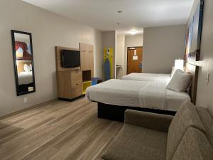 - une chambre avec un lit, un canapé et une télévision dans l'établissement Days Inn by Wyndham Oklahoma City, à Oklahoma City