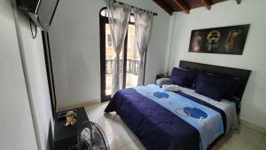 a bedroom with a bed with blue sheets and a window at amplio y comodo apartamento en envigado in Envigado