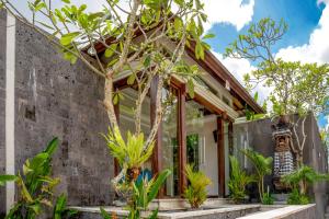 a home with a concrete wall and trees at Sanata Luxury Villa in Canggu