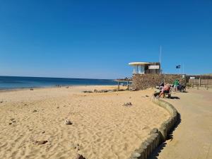 - une plage avec des personnes assises sur le sable et l'océan dans l'établissement Maison Bretignolles-sur-Mer, 2 pièces, 4 personnes - FR-1-231-140, à Bretignolles-sur-Mer