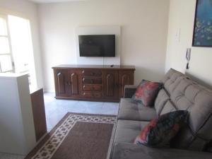 a living room with a couch and a flat screen tv at Apartamento Das Flores in Gramado