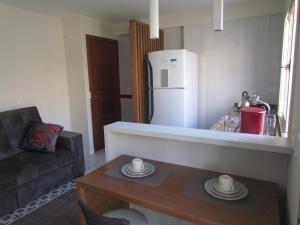 a kitchen with a table and a white refrigerator at Apartamento Das Flores in Gramado