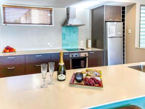 a kitchen with a counter with a plate of food and wine glasses at The Moorings Waterfront Picton in Picton