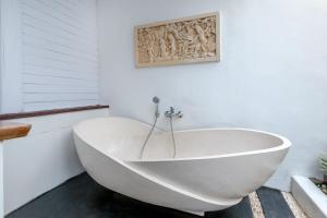 eine weiße Badewanne im Bad mit einem Bild an der Wand in der Unterkunft Elysium Bingin in Uluwatu