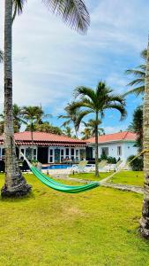 una hamaca entre dos palmeras frente a una casa en PALM HOUSE - LUXURY VILLA - SAMANÁ - Ocean Front en Sánchez
