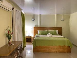 a bedroom with a large bed with a green blanket at Bosque Azul de Osa in Rancho Quemado