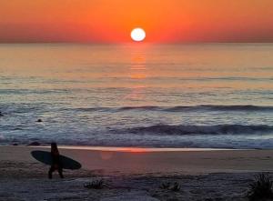 een persoon die op het strand loopt met een surfplank bij H2A in Aroeira