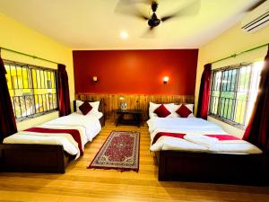 two beds in a room with red walls and windows at Chitwan Safari Resort in Sauraha +6 photos