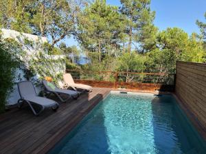 einen Pool mit zwei Stühlen auf einer Holzterrasse in der Unterkunft Les Jardins d Eve Solenzara townhouse with private pool in Favone