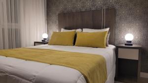 a bedroom with a large bed with yellow pillows at Be Haus Temporary Apartments in San Luis