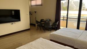 een hotelkamer met een televisie en een tafel en stoelen bij Sharkat Homestay in Magong