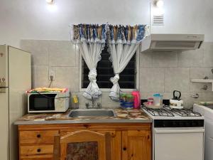 a kitchen with a sink and a microwave at Casa May - A 15 min del Aeropuerto in Barrio Esteban Echeverría