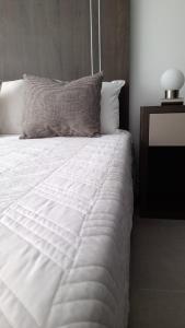 a bed with a white comforter and a pillow at Be Haus Temporary Apartments in San Luis