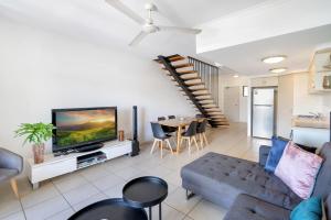 a living room with a couch and a tv and a table at The Loft Cairns in Cairns
